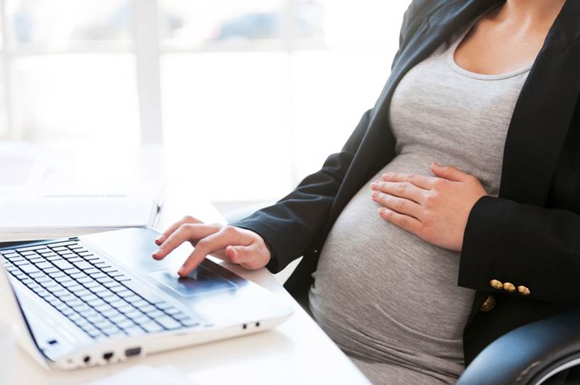 Pregnant woman sitting in chair at work - Pregnancy Discrimination